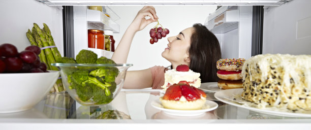 女人在吃冰箱里的葡萄图片下载