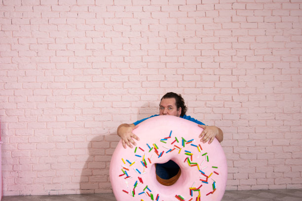 滑稽的胖子梦见甜甜圈和蛋糕。图片下载