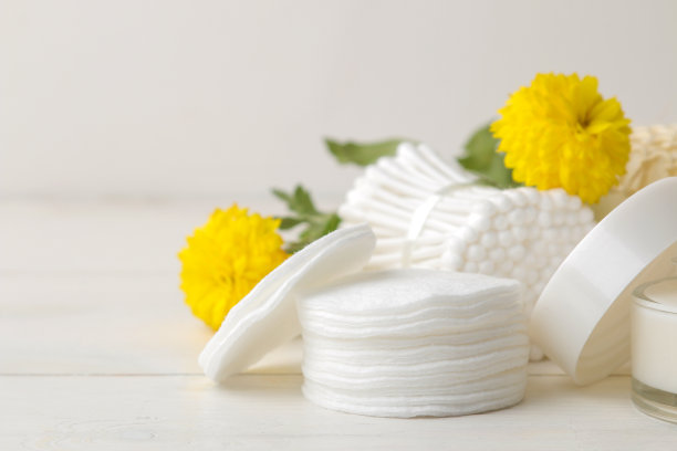各种个人护理产品。化妆棉特写，白色背景上的木棍和黄花图片下载