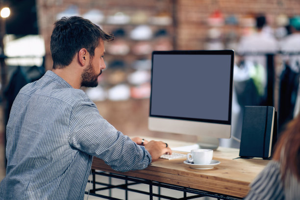 年轻人看着屏幕上的文字。一个在电脑上工作的人。图片下载