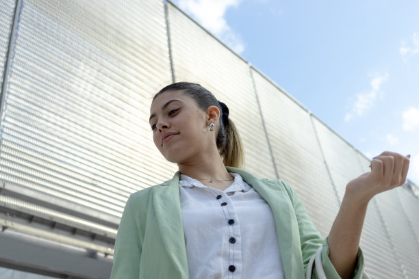 站在公司大楼门口的年轻女子。穿着优雅。图片下载