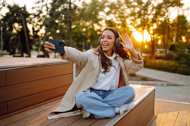 快乐的年轻女子拿着手机，通过无线耳机听音乐。图片下载