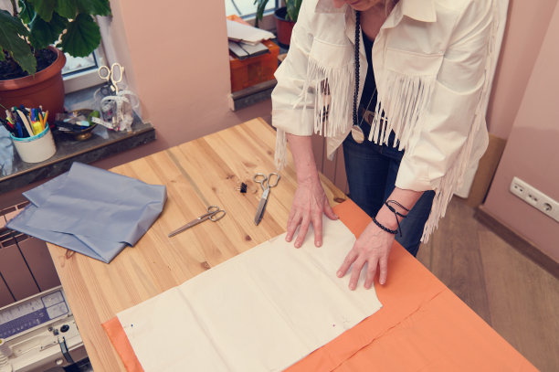 在一个裁缝工作室里，时装设计师把缝纫图案放在奢侈的面料上，同时为新的系列创造新的服装。图片下载