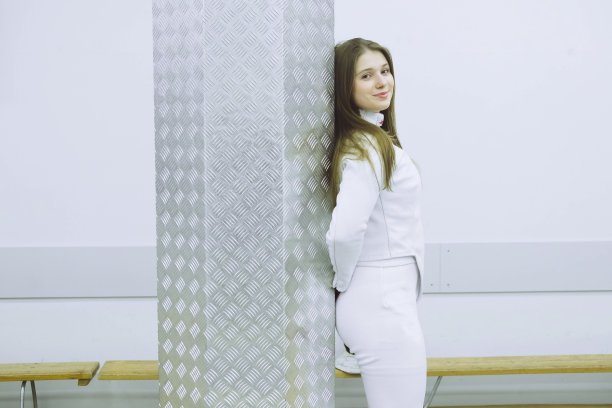 穿着白色运动服的女孩，带着一把剑在训练。击剑运动图片下载