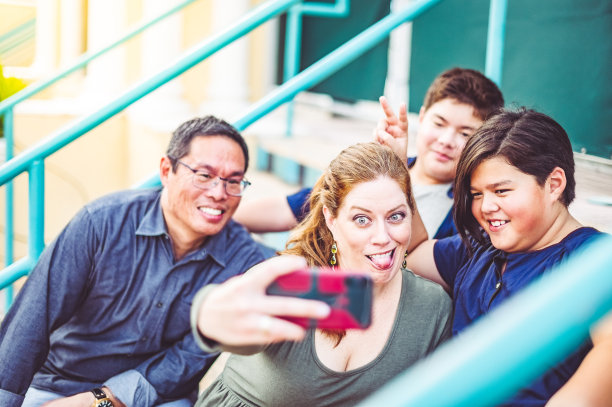 妈妈用手机自拍她的多种族家庭在户外做鬼脸图片下载