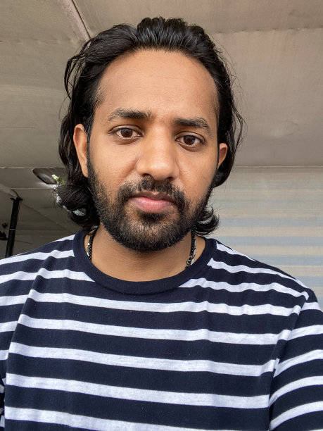 特写图片:蓬头垢面的印度男子用手机自拍，举着手机，低头看着手机屏幕自拍，凌乱的头发，休闲的衣服，聚焦在前景图片下载