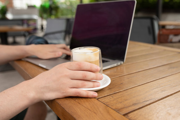 咖啡厅里拿着咖啡杯和笔记本电脑的闲人。图片下载