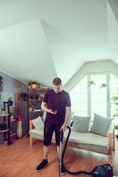 男性在家吸尘时使用智能手机图片下载