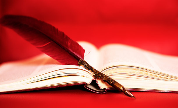 一本打开的书和一支红色背景上的笔图片下载