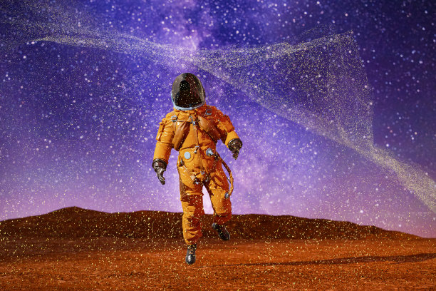 红色沙漠星球上身着橙色宇航服的宇航员图片下载