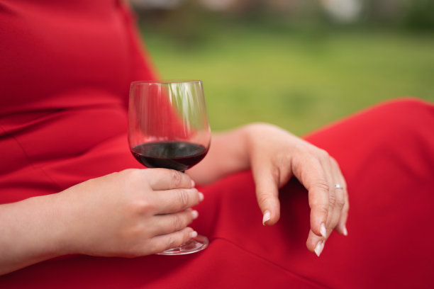 一个穿红裙子的女孩端着一杯酒图片下载