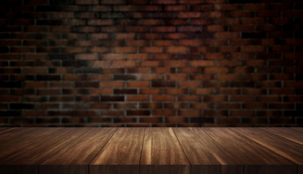 空木桌与复古砖墙背景的产品植入。在黑暗的室内房间里，前景是棕色的木桌。质朴的木桌，中间有灯。图片下载
