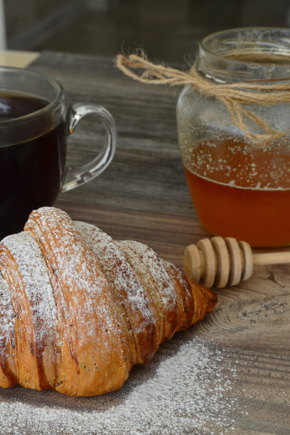 桌上放着牛角面包和咖啡，还有一罐蜂蜜图片下载