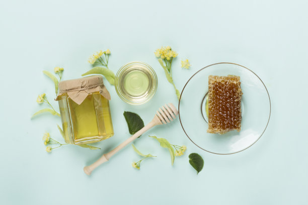 菩提树蜂蜜与叶和花的彩色背景，俯视图图片下载