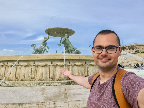 一名年轻人在马耳他瓦莱塔的Tritons喷泉前自拍图片下载