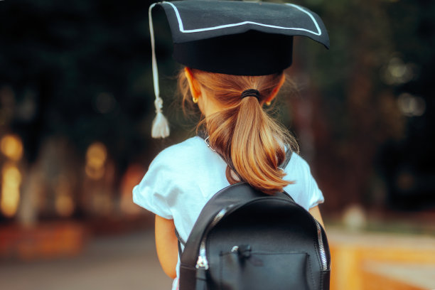 小女孩背着书包，戴着学位帽图片下载