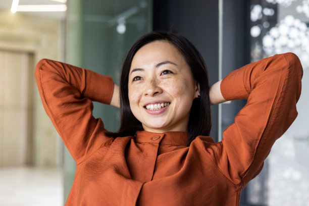 美丽的亚洲商务女性在办公室休息，商务女性双手放在脑后，对工作结果满意，使用笔记本电脑，特写照片图片下载