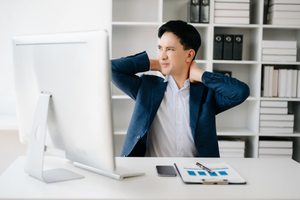 劳累过度的年轻亚洲商人办公室职员在办公桌前工作了一整天后颈部疼痛。办公室综合症概念图片下载