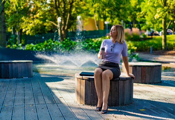 美丽的中年女人坐在城市公园的长椅上图片下载