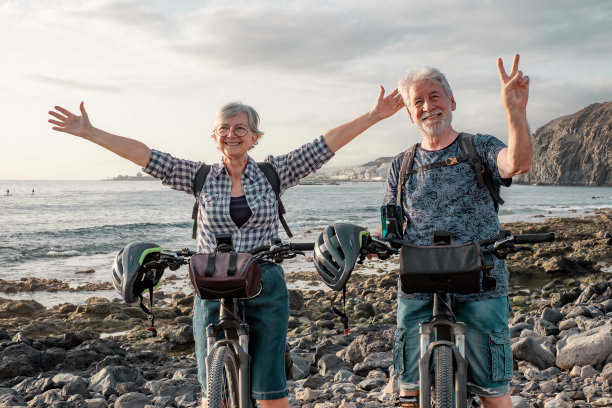一对运动健将夫妇在沙滩上骑自行车。老年人在度假或退休时表达满意和自由图片下载