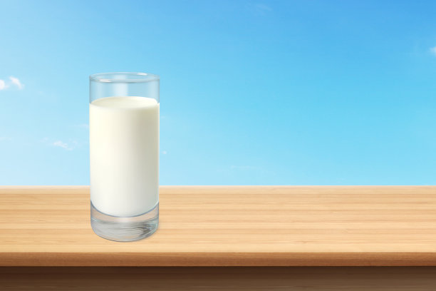 木桌上的一杯牛奶，背景是天空图片下载