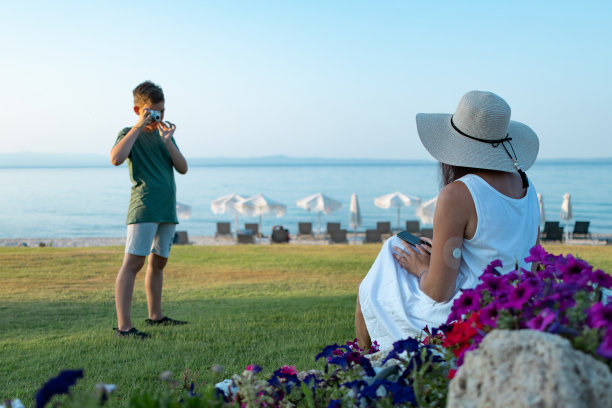 男孩正在海滨附近的公园里给他的妈妈拍照。家庭度假。图片下载