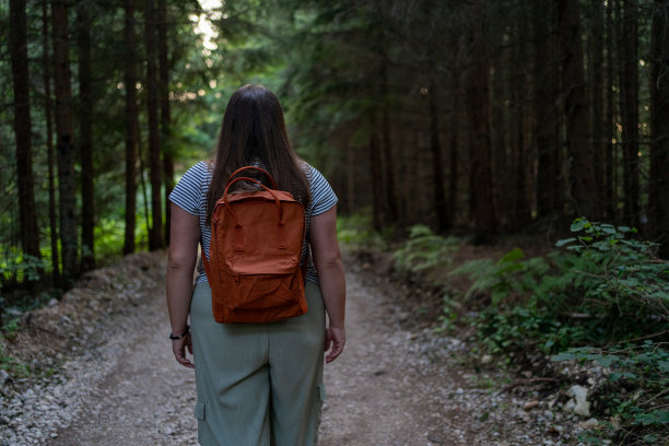 一个穿着随意的年轻女子背着背包独自探索森林的后视图图片下载