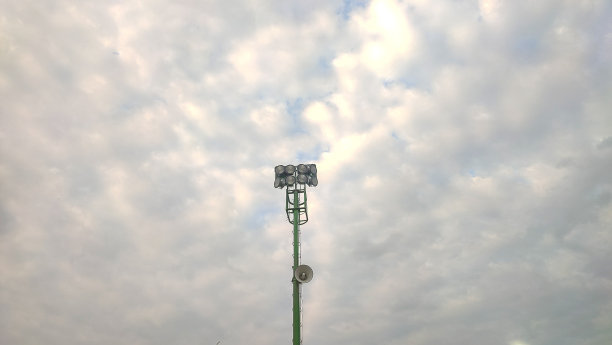 聚光灯杆，电线杆和运动灯在云的背景下图片下载