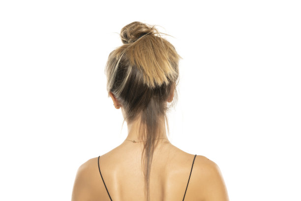 在工作室的白色背景上，一个凌乱松散的发髻的女人。后视图图片下载