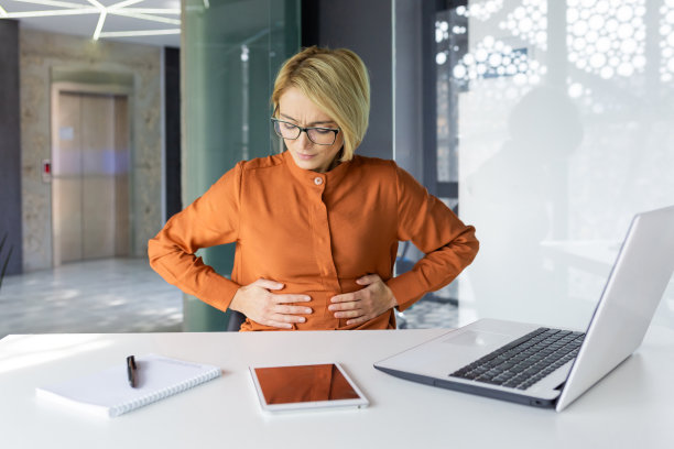 生病的女人独自在工作场所有严重的胃痛，女商人食物中毒在办公室有胃灼热和腹泻图片下载
