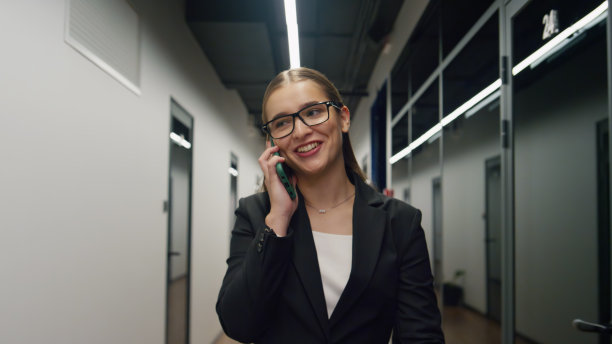 快乐的高管在打电话。成功的女商人走在走廊上图片下载