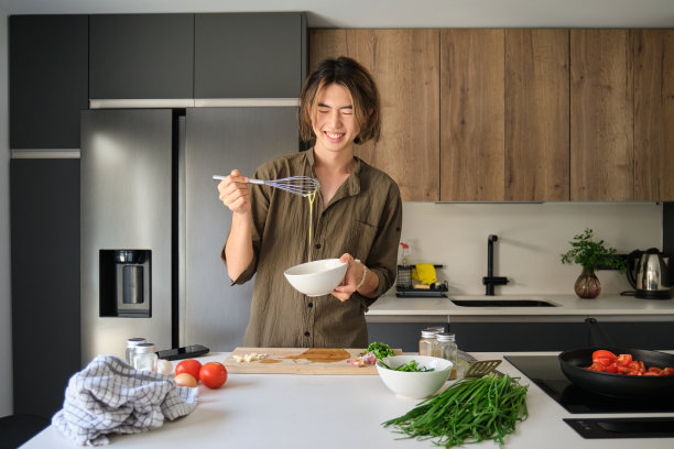 亚洲年轻人在厨房打鸡蛋。图片下载