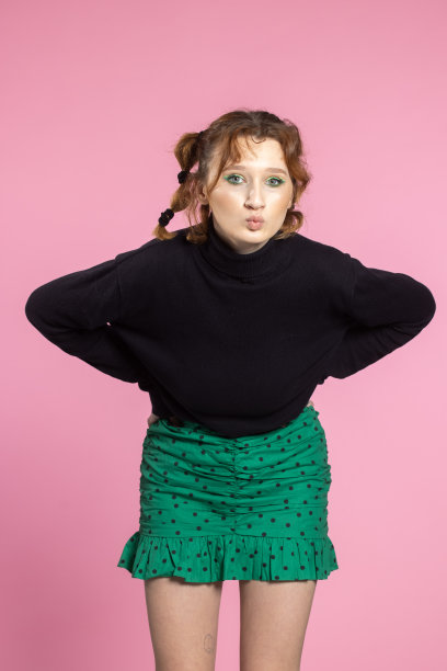 友好的年轻女子，面带活泼的微笑，情绪激动。年轻的红发女孩在粉红色的背景图片下载