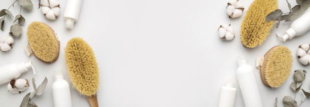 木制身体按摩刷与自然鬃毛，白色清洁化妆品瓶，桉树枝，棉花花在灰色背景。健康美丽的有机配件。水疗产品。平躺图片下载