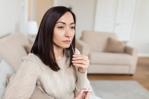 一名妇女使用棉签进行冠状病毒PCR检测的照片。一名女子在家从鼻子中提取冠状病毒样本。在家使用鼻拭子检测COVID-19的妇女。图片下载