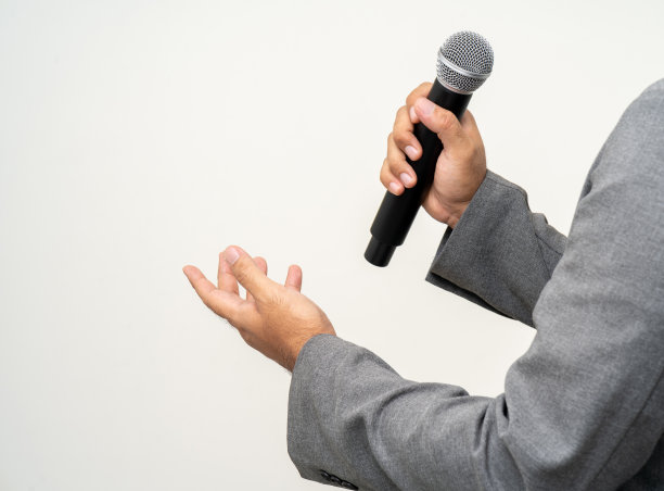 近距离商人扬声器手持高品质的动态麦克风和唱歌或说话与人交谈孤立的白色背景。男性为面试测试麦克风声音图片下载