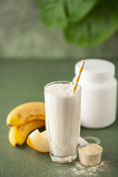 一杯甜瓜香蕉奶昔或奶昔，甜瓜片，香蕉放在桌子上。图片下载