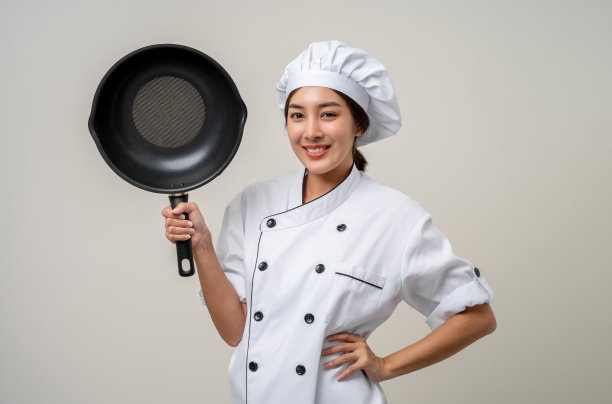 年轻漂亮的亚洲女厨师，穿着制服，拿着锅子和铁煎锅器具在厨房里烹饪，在孤立的背景下各种姿势。女职业厨师餐厅和酒店。图片下载
