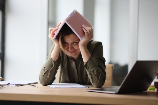 办公室里的女人藏在头上的笔记本下面图片下载