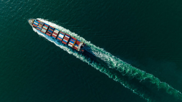 货运集装箱船在海上全速航行，进出口货物，并将产品分销给全球经销商和消费者，集装箱船运输业务交付服务，航拍视图图片下载