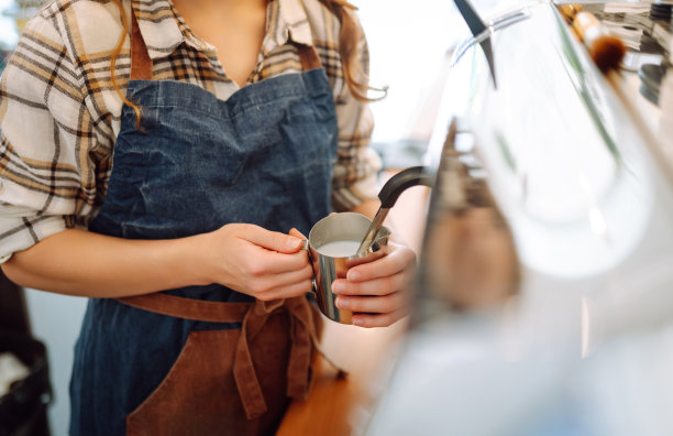 一位年轻的女咖啡师正在制作新鲜咖啡。图片下载