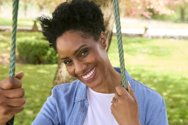 一个面带微笑的成熟女人坐在户外的花园秋千上图片下载