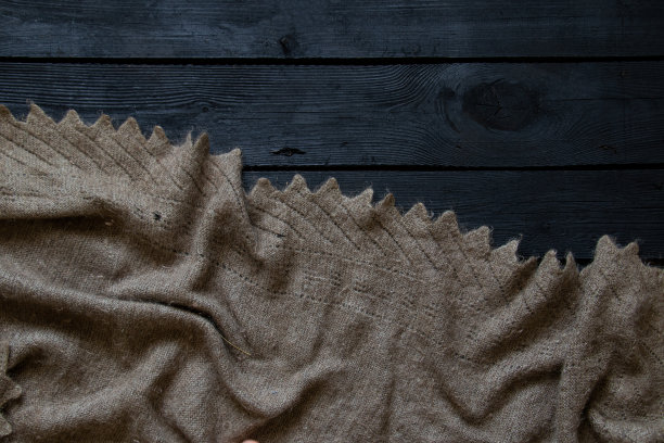 一条老祖母的羊毛围巾躺在黑色木地板上，作为背景、时尚和装饰图片下载