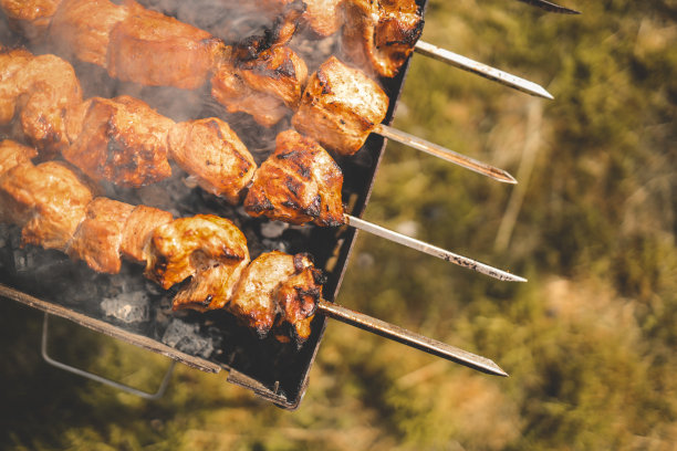 白天，一名男子在后院用手烧烤熏猪肉。家庭聚餐户外式烧烤活动图片下载