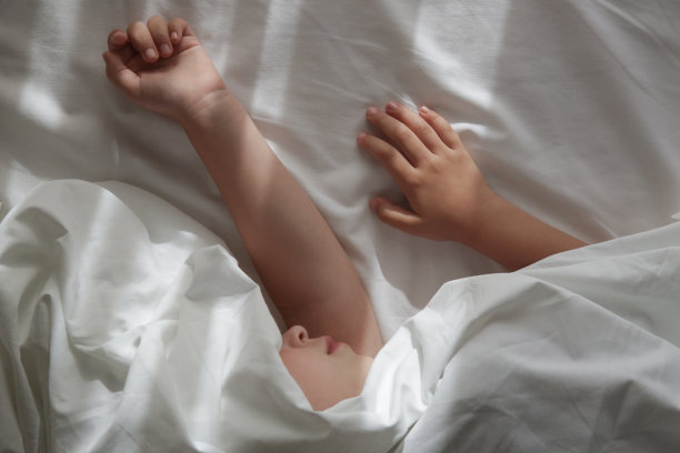 安静的小女孩睡在铺着洁白床单的床上。安静的小女孩睡在舒适的白色床上图片下载
