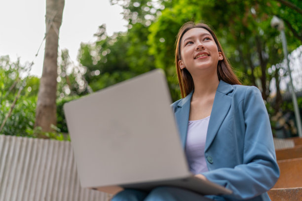 自然的办公室。亚洲女商人在公园用笔记本电脑赚钱。走出家门。混合动力工作图片下载