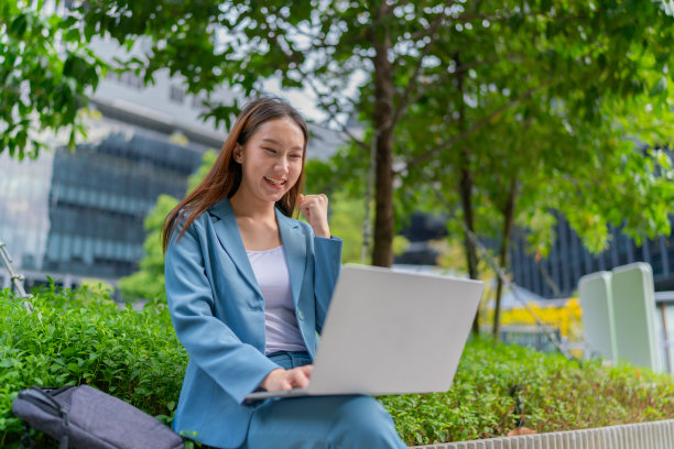 自然的办公室。亚洲女商人在公园用笔记本电脑赚钱。走出家门。混合动力工作图片下载