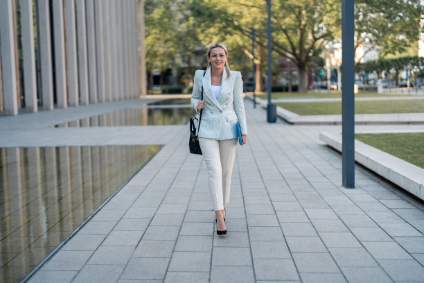 迷人微笑的年轻女商人下班后拿着笔记本回家图片下载