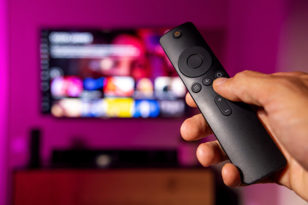 手里拿着遥控器，背景是电视。流媒体服务，内容点播。在家看网络电视图片下载
