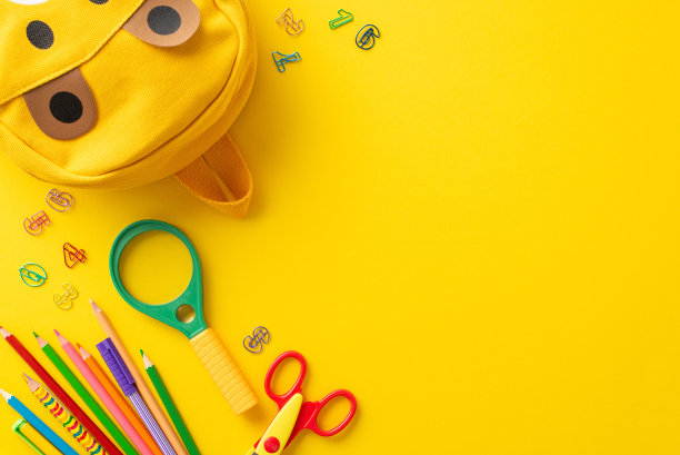 Education-themed显示。高角度拍摄，在黄色的隔离面上捕捉可爱的儿童背包和各种各样的学习资料，留出文字或宣传内容的空间图片下载
